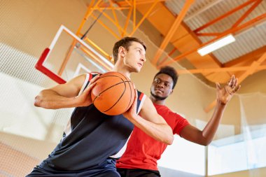 Genç adam basketbol oynarken birlikte spor salonunda hedef çekim yarışmacı durdurmaya siyah.
