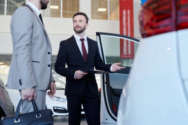 Müvekkilinin araba salonu için yeni bir araba gösteren profesyonel araba satıcısı
