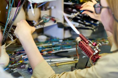 Glassworking studio, güzel el yapımı takı boncuk yaparken Gaz Meşalesi tarafından Cam eritme tanınmaz halde kadın sanatçının yakın çekim