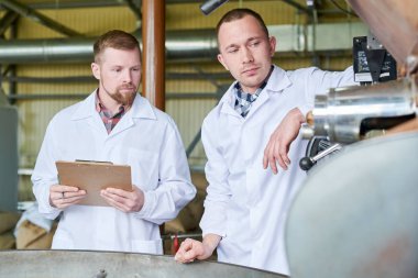 Belden yukarı iki adam çalışırken modern roastery kahve işleme tartışırken laboratuvar mont giyiyor portresi