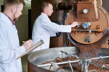 Yan görünüm portre iki modern genç adamın davul makinesi roastery, kopya alanı çalışırken çalışma laboratuvar mont giyiyor