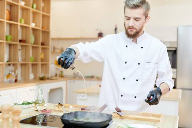 Ahşap masada duran ve yağlar lezzetli yemekleri, kopya alanı ekleme modern restoran mutfakta çalışan yakışıklı profesyonel şef portresi