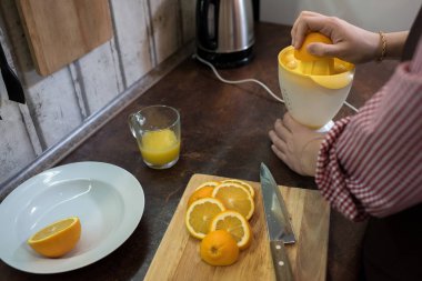 Mutfak tezgahının duran ve lezzetli portakal suyu yapmak için suyu kullanarak kırpma genç adam. 