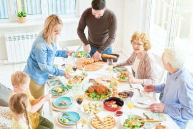 Büyük mutlu aile zevk yemeğe birlikte portresi yüksek açı yuvarlak lezzetli yemekleri ile şenlikli masa genç kadın yemekleri sunan tatil kutlaması sırasında oturan kopyalama alanı