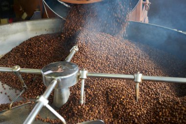 Yüksek açı arka planını yerel esnaf roastery, kopya alanı davul makinesinde kavurma için dökülmesini krem kahverengi kahve çekirdekleri