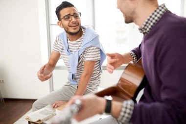 Çok etnik gruptan oluşan takım yöneticilerinin iş mola: onlar birlikte modern ofis ve şarkı toplanan gitar için