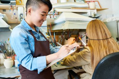 Meslektaşım cam modern glassworking Studio, kopya alanı ile çalışan konuşurken önlük giyen gülümseyen Asya kadın portresi
