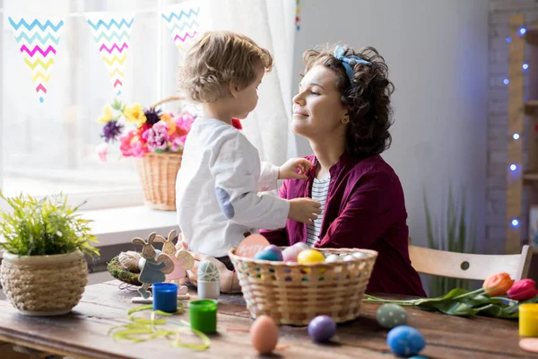 Portrait of pretty young mother playing with  little boy while celebrating Easter at home, copy space