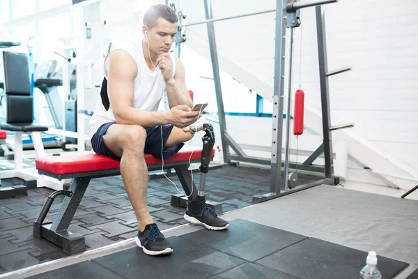 Ung Man Sitter Och Lyssnar Musik Sin Telefon Gymmet — Stockfoto