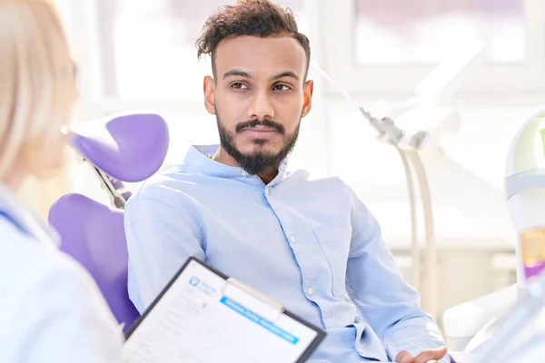 Portret Młodego Człowieka Bliskiego Wschodu Siedząc Fotel Dentystyczny Słuchać Lekarza — Zdjęcie stockowe
