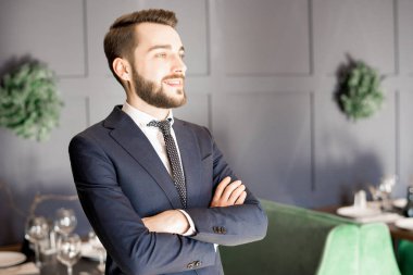 Tek başına kuruluş alanı düşünürken ve uzağa bakarak çapraz silah gurur ile neşeli pozitif maksatlı yakışıklı Restoran sahibi