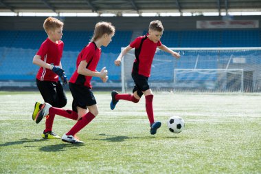 Üç erkek kırmızı genç takım antrenman sırasında kopya alanı futbol tarlada çalışan üniforma giyen tam uzunlukta portresi