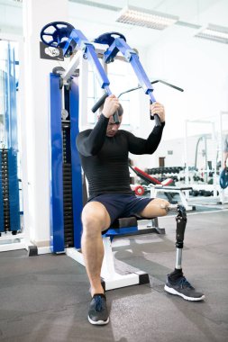 Protez bacak modern spor salonunda makinasıyla ağırlıkları ile çalışma dışarı ile yakışıklı kaslı adam portresi tam uzunlukta