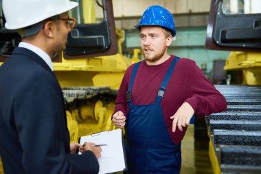 Ağır makineleri karşı modern duran atölyesinde Ortadoğu iş adamı konuşurken fabrika işçisi portresi
