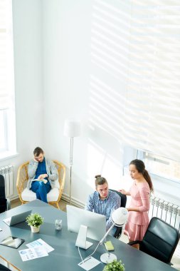 İspanyol iş kadını genç programcı ofis rahat koltukta oturuyor ve istemciler arama hipster Yöneticisi bilgisayar kullanarak çalışmalarını inceleyerek görünümünü hemen üstüne.