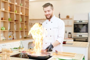 Bel kadar modern restoran mutfak ayakta ahşap masa ve pişirme flambe çanak, kopya alanı çalışma gülümseyen profesyonel şef portresi