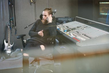 Şık operatör modern stüdyo kayıt ve arama smartphone sahip oturan sakallı. 