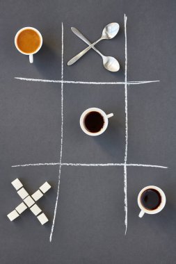 Tic tac toe tasarım, kopya alanı ile gri arka plan üzerinde çapraz kaşık, kahve fincanı ve kesme şeker üstten görünüm