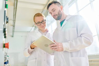 Grup yoğun teknoloji kalite kontrol modern Süt Fabrikası'nda tamamlanmasından sonra dijital tablet üzerinde gerekli notlar alarak beyaz ceket giyiyor