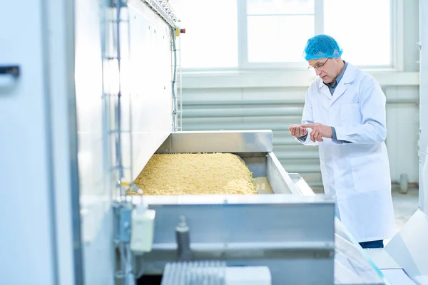 マカロニ コピー スペース マシン単体で立っている食品工場での品質検査を行うシニア工場労働者の肖像 — ストック写真