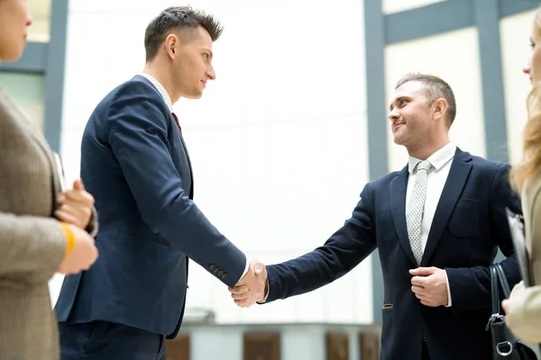事務所の契約に署名した後握手を行うフォーマルなスーツで自信を持ってハンサムな若いビジネスマンをコンテンツします — ストック写真