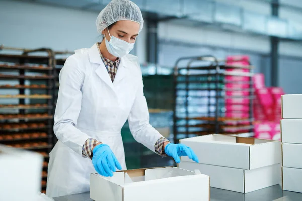 工場で空の紙箱を準備する白衣のお菓子メーカー — ストック写真