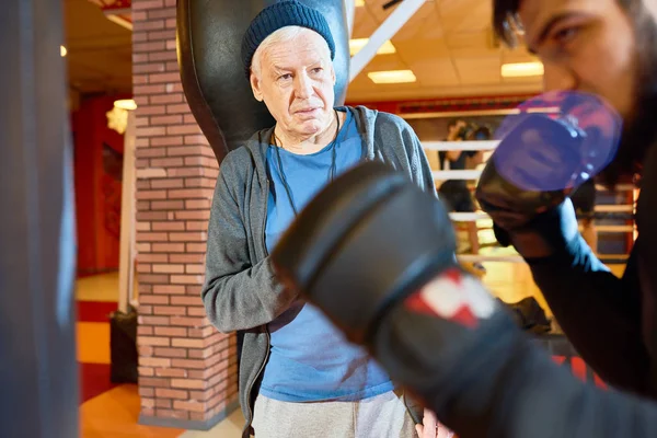 Waist up portrait of senior coach training fighter at boxing practice in martial arts club