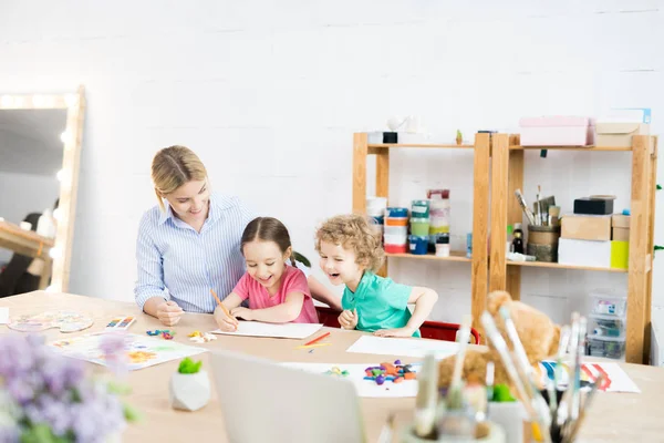 stock image Portrait of two happy children enjoying art and craft lesson with young teacher in development school, copy space