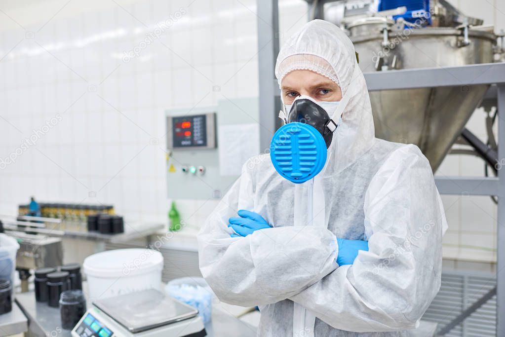 Sports nutrition production worker standing in protective clothing with arms crossed and looking at camera.