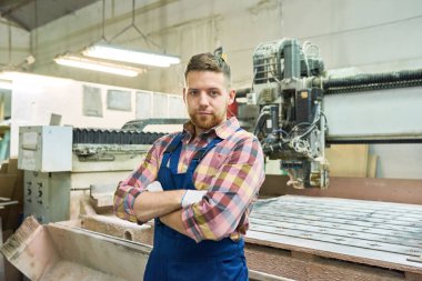 Bel genç fabrika işçisi iken ayakta kollarını çapraz kameraya bakarak portresi kadar alanı kopyalama modern atölye, ağaç kesme makinesi tarafından poz