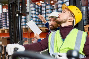 Yan görünümü yukarıya bakıp arka planda, kopya alanı talimatlar vermek Danışmanı ile mal taşıma forklift arabada oturan genç adam portresi