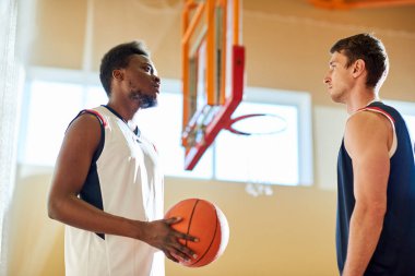 Sahada ayakta ve birbirine maç başlamadan önce bakarak iki basketbol oyuncuları yan görünüm. 