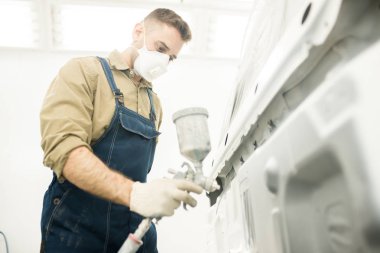 Koruyucu maske resim kamyon genç profesyonel tamirci airbrush sprey tabanca atölye ile düşük açılı görünümü