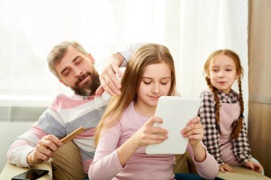Sevgi dolu baba evde hafta sonu harcama: o küçük kızı o dijital tablet, onlara göz kulak şirin kız kardeşi Internet tarama sırasında saç tarama