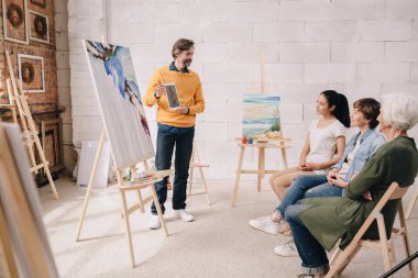 Olgun sanatçı ders öğrencilere modern Studio suluboya resim sunan tam uzunlukta portresi