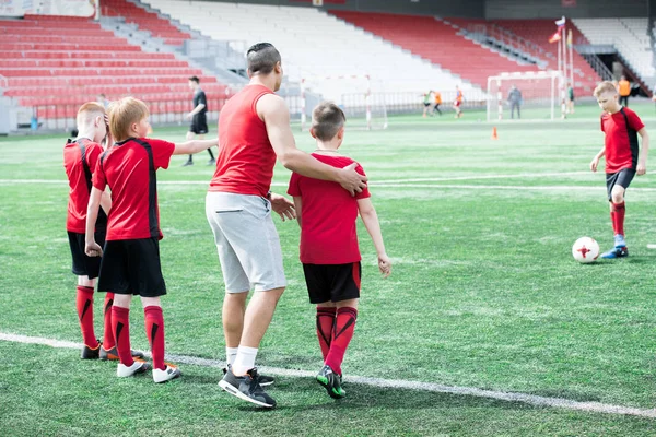 Tam uzunlukta portre genç çalıştırıcı ile açık stadyum pratik genç futbol takımı