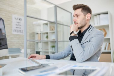 Siyah gömlek ve resepsiyon ve bitirme projesi bilgisayar, iç arka plan üzerine açık plan Office Yardımı ile oturan ceket giyen çalışkan sakallı girişimci