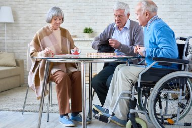 Grup, cam masa oturma odasında oturmak loto oyunu oynarken üst düzey insan tam uzunlukta manzaraya