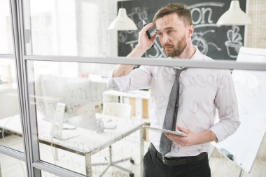 Çözüm düşünme ve modern ofisindeki camsı tahtada yazılan web komut dosyası çözümlenirken kafa dokunmadan ciddi düşünceli yakışıklı genç erkek programcı