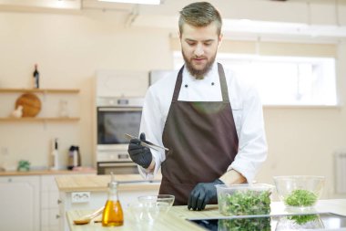 Bel kadar yakışıklı sakallı Şef restoran mutfak ayakta ahşap masa, kopya alanı, yemek portresi