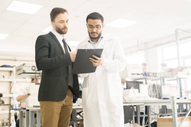 Laboratuvar önlüğü ve potansiyel yatırımcı işbirliğini basınç detektörler Fabrikası'nın geniş dairesindeki dururken ayrıntılarını tartışarak yakışıklı Arap teknisyen