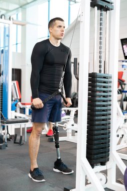 Protez bacak ağırlık makinasıyla modern güneşli spor salonunda dışarı çalışırken ile yakışıklı kaslı adam portresi tam uzunlukta
