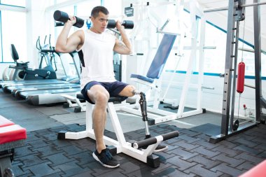 Spor salonunda egzersiz yapan genç amputee erkek