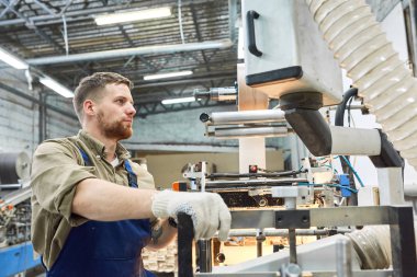 Yan görünüm portre genç fabrika işçisi işletim makine birimi atölyede, kopya alanı