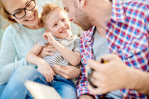 Warm toned portrait of happy loving family playing with cute son sitting on floor in living room  together