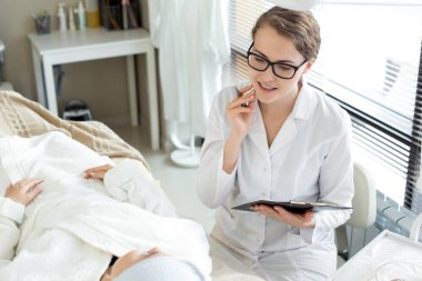 Güzellik uzmanı holding Pano gülümseyen ve notlar ofis sırasında istemciye yönergeler verirken yapma portre