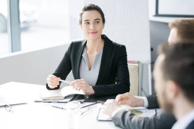 Brifing sırasında tablo konferans salonunda toplantı oturan arkadaşları dinlerken gülümseyen kendine güvenen genç işkadını portresi