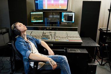 Kayıt stüdyosu konsol oturan zevk ile müzik kulaklık şık adam yan görünüm. 