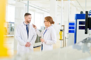 Takım ve beyaz önlük geniş paketleme bölümünde duran güzel gazeteci röportaj veren modern Süt Fabrikası'nın yakışıklı sakallı sahibi