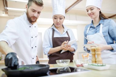 Takım modern restoran mutfak ayakta çalışma profesyonel şefler düşük açılı manzaraya ahşap masa yuvarlak ve birlikte, lezzetli yemekleri pişirme alanı kopyalayın